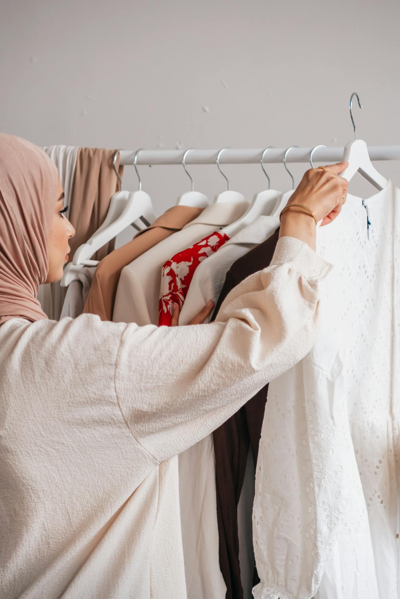 A woman in a hijab choosing clothes from a wardrobe. Fashion and cultural representation.