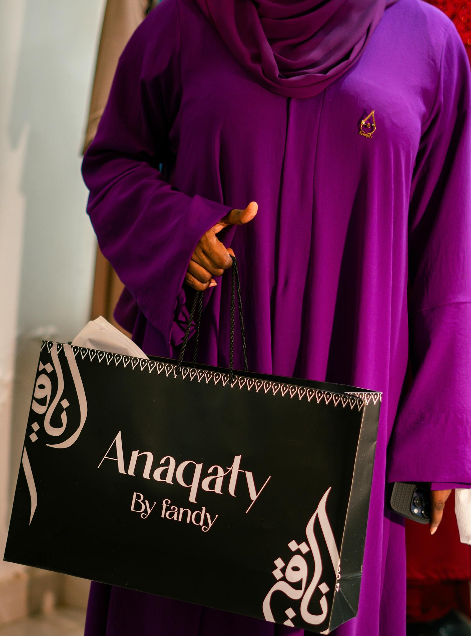 Elegant woman in purple holding an Anaqaty shopping bag.