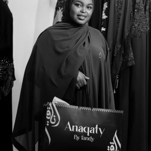 Stylish woman holds Anaqaty shopping bag in elegant boutique.
