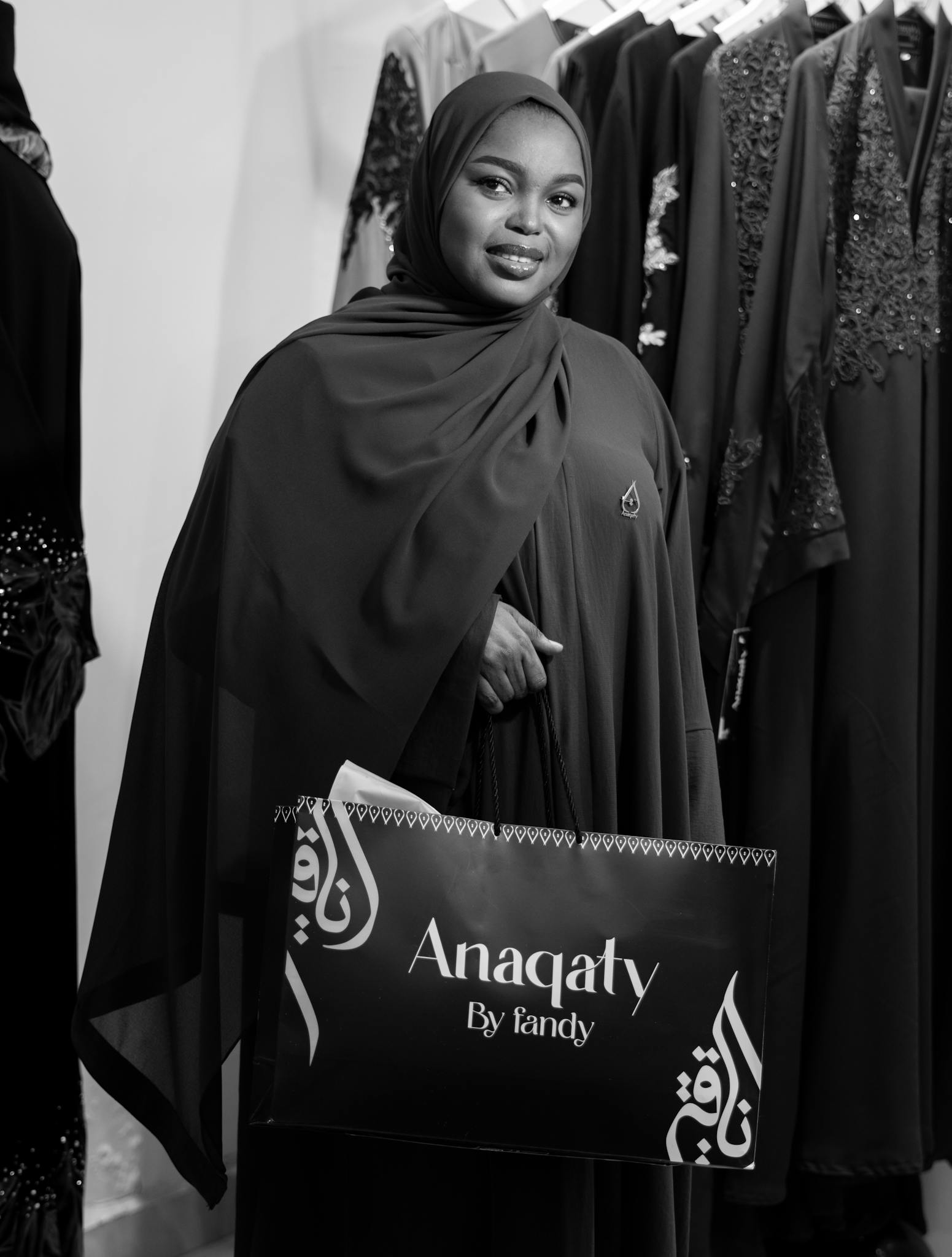 Stylish woman holds Anaqaty shopping bag in elegant boutique.
