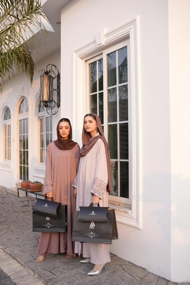 Two women in elegant hijabs and modest fashion pose outdoors during daylight.