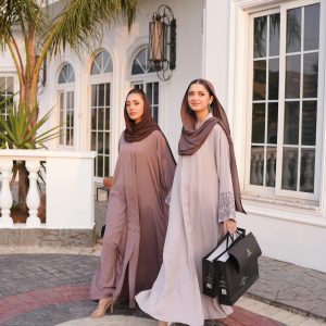 Two women in elegant modest fashion outfits with hijabs walking outdoors.