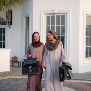 Two women wearing hijabs and modest fashion outfits carrying shopping bags outdoors.